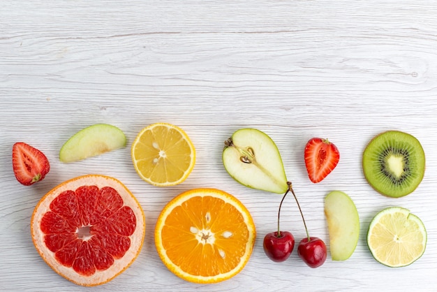 Una composizione nella frutta fresca di vista superiore affettata dolce e succosa su bianco, foto a colori della frutta matura