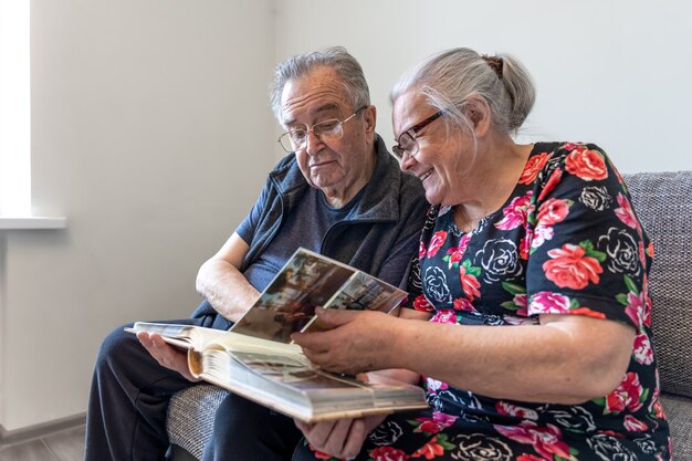 Una coppia di anziani sta guardando le fotografie in un album di foto di famiglia.