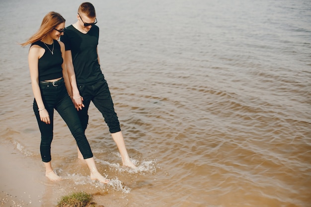 Una coppia elegante e bella in abiti neri passa un buon tempo in spiaggia