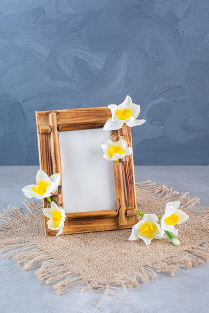 Una cornice in legno con fiori bianchi su un sacco.