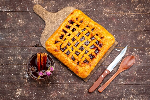 Una deliziosa torta di fragole vista dall'alto con gelatina di fragole insieme al tè sullo zucchero del biscotto della torta della scrivania in legno