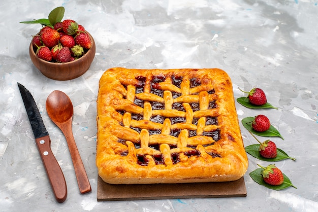 Una deliziosa torta di fragole vista frontale con gelatina di fragole all'interno insieme a fragole fresche sulla torta da scrivania grigia