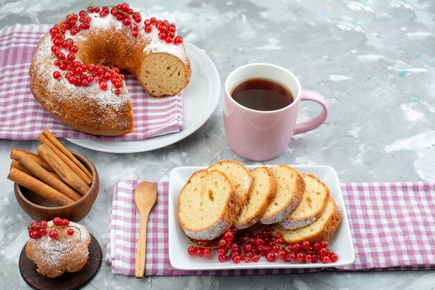 Una deliziosa torta di vista frontale con cannella di mirtilli rossi freschi e tè sullo zucchero bianco della bacca del tè del biscotto della torta della scrivania