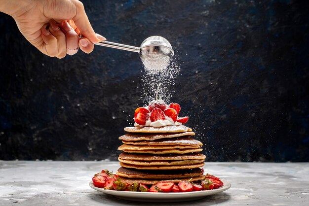 Una deliziosa vista frontale frittelle rotonde con panna e fragole rosse torta di frutta cuocere