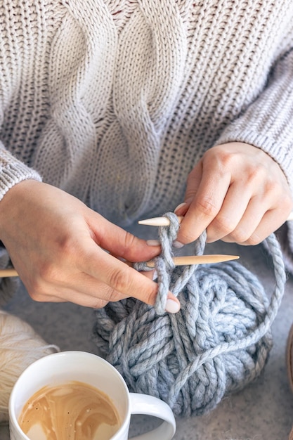 Una donna a maglia con un filo grigio in primo piano