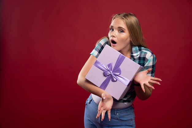 Una donna bionda tiene stretta una scatola regalo e diventa gelosa di condividerla.