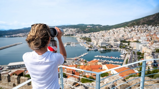 Una donna che guarda nel binocolo stazionario a Kavala, Grecia