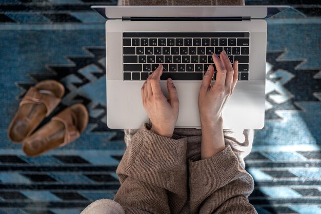 Una donna che lavora seduta a una vista dall'alto di un laptop