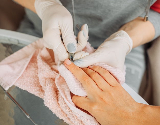 Una donna che riceve manicure da una donna in guanti e maschera nel salone di bellezza durante il giorno