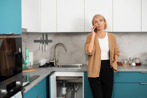 Una donna chiama un idraulico per risolvere problemi in cucina.