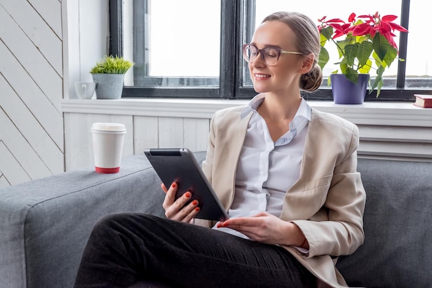 Una donna con gli occhiali che lavora con il tablet PC.