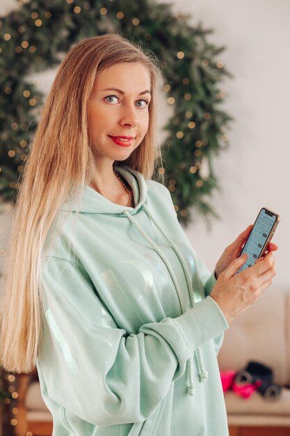 Una donna con un telefono in mano una donna con i capelli lunghi mostra un'applicazione su un telefono cellulare