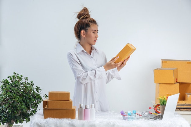 Una donna d'affari sta lavorando online e trading per rispondere all'imballaggio del cliente a casa ufficio sulla parete.