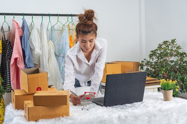 Una donna d'affari sta lavorando online e trading per rispondere all'imballaggio del cliente a casa ufficio sulla parete.