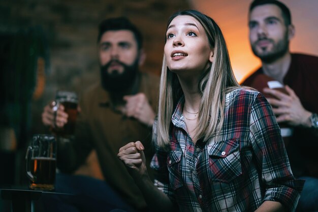 Una donna eccitata e le sue amiche fanno il tifo per la loro squadra mentre guardano la partita sportiva in TV a casa