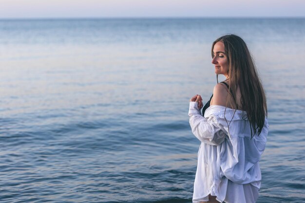 Una donna in costume da bagno e una camicia bianca in mare