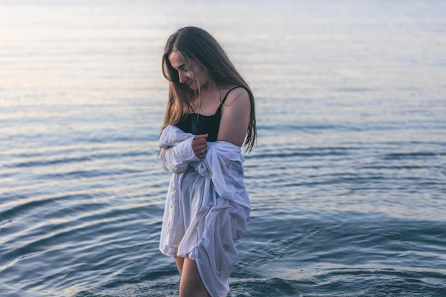 Una donna in costume da bagno e una camicia bianca in mare