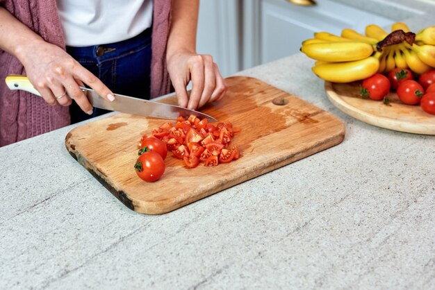 Una donna in cucina tagliare i pomodori per insalata