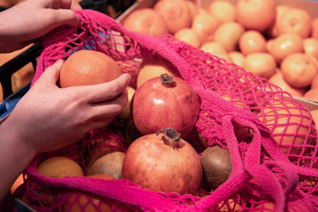 Una donna in un supermercato mette la frutta in una borsa della spesa