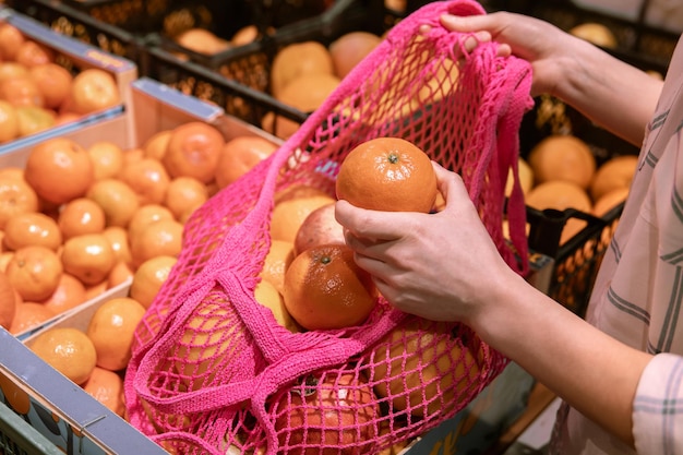 Una donna in un supermercato mette le arance in una borsa della spesa