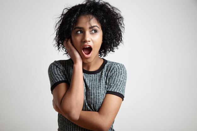 Una donna nera con i capelli corti e ricci che si chiedeva che guardava da parte