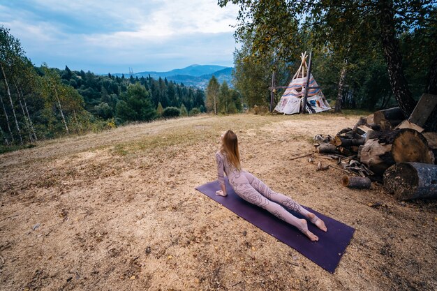 Una donna pratica yoga al mattino in un parco all'aria aperta.