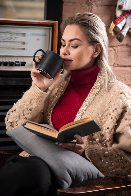 Una donna seduta con un libro e bere caffè