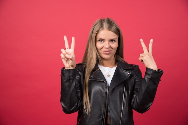 Una donna sorridente che indossa abiti casual che guarda la telecamera e mostra le dita