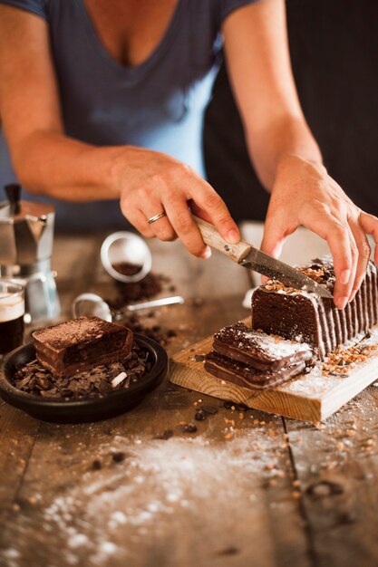 Una donna taglio fetta di torta con coltello sul tagliere