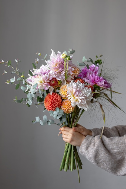 Una donna tiene in mano un bouquet festivo con fiori di crisatemo.
