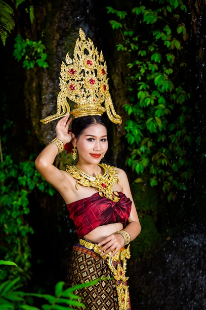 Una donna vestita con un abito thailandese antico presso la cascata.