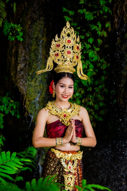 Una donna vestita con un abito thailandese antico presso la cascata.