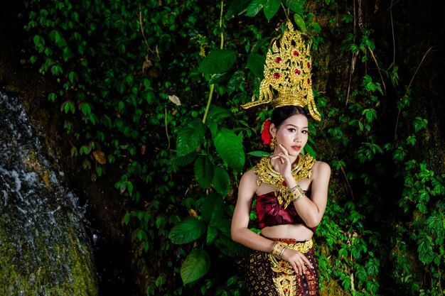 Una donna vestita con un abito thailandese antico presso la cascata.