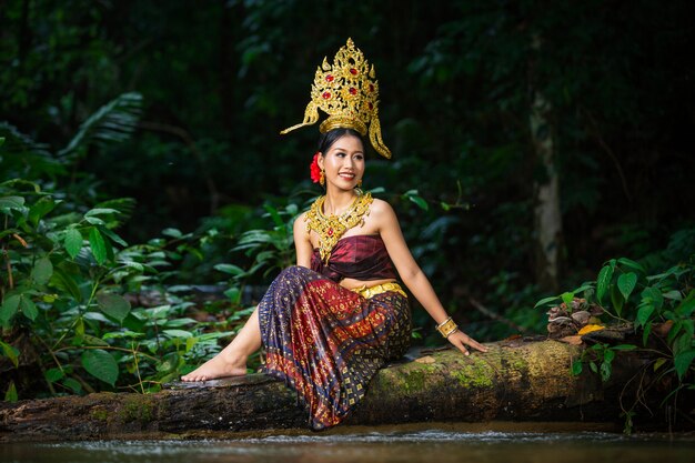 Una donna vestita con un antico abito thailandese alla cascata.
