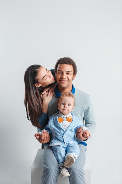 Una famiglia felice dell'uomo afro e donna e bambino caucasici sullo studio bianco