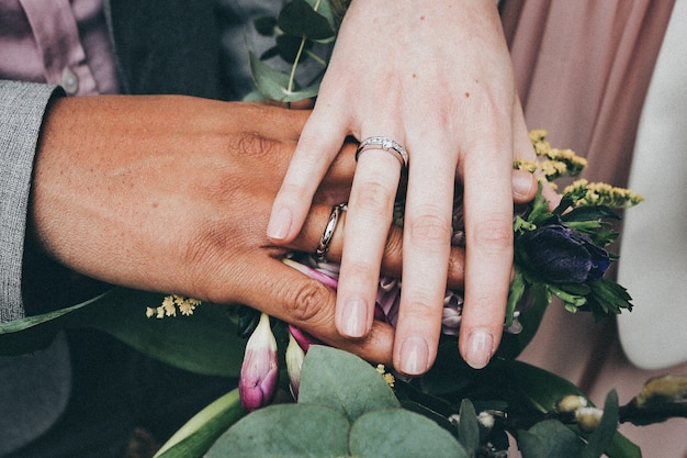 Una femmina caucasica e un maschio afroamericano indossano anelli e tengono i fiori Concetto di diversità