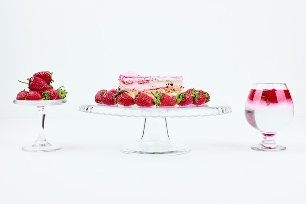 Una fetta di cheesecake alla fragola con frutta e un bicchiere di bevanda.