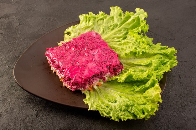 Una fetta di insalata di barbabietole vista frontale chiusa di insalata di maionese con piatto marrone interno verde