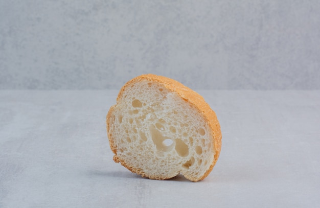 Una fetta di pane bianco fresco rotondo su fondo di marmo.