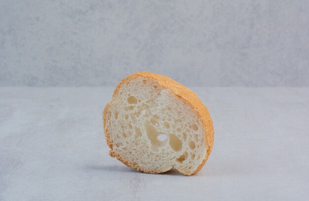 Una fetta di pane bianco fresco rotondo su fondo di marmo.