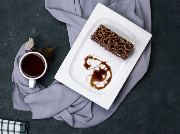 Una fetta di torta al caramello con cioccolato tritato nel piatto bianco.