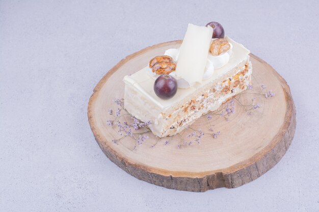 Una fetta di torta al cocco con uva e noci su una tavola di legno