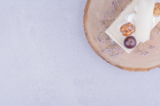 Una fetta di torta al cocco con uva e noci su una tavola di legno