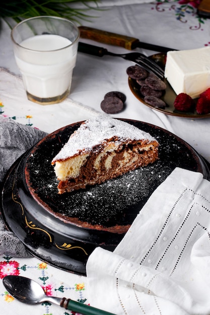 Una fetta di torta giorno e notte cosparsa di zucchero in polvere servita con latte