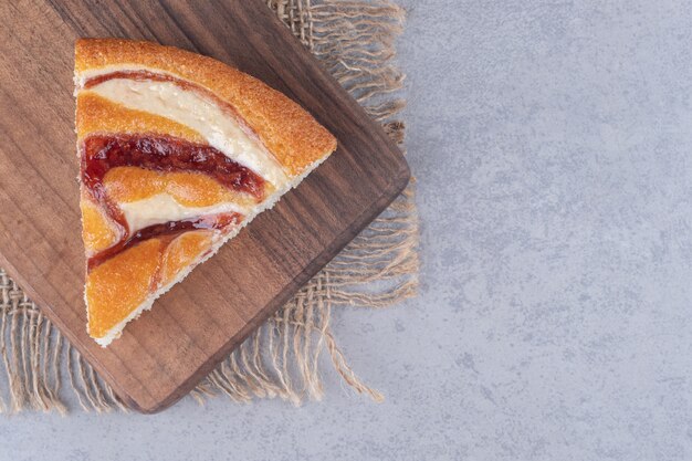 Una fetta di torta su una tavola di legno sul tavolo di marmo.