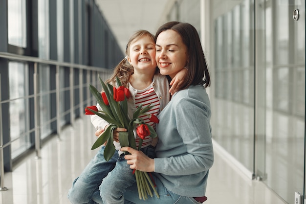 Una figlia sta dando alla mamma un mazzo di tulipani rossi