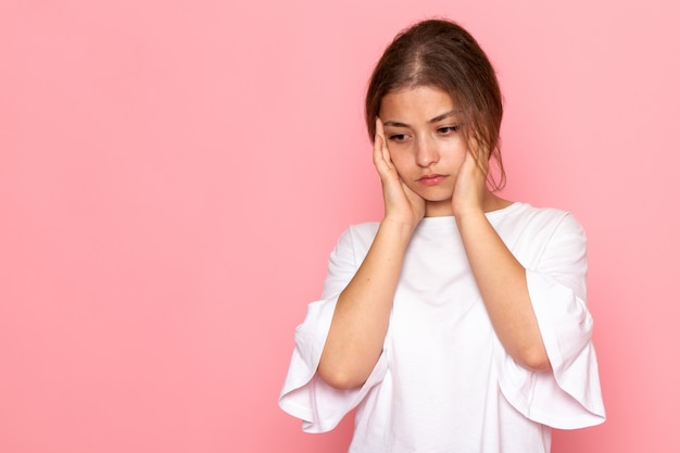 Una giovane bella femmina di vista frontale in camicia bianca che posa con l'espressione di pensiero