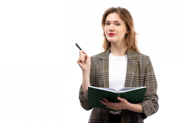 Una giovane bella signora di vista frontale in jeans neri e cappotto della maglietta bianca che tengono libro verde sul bianco