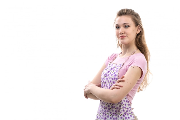 Una giovane casalinga attraente di vista frontale nella posa sorridente del capo variopinto della camicia rosa sulla femmina bianca della cucina di cucina del fondo