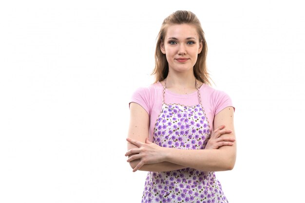 Una giovane casalinga attraente di vista frontale nella posa sorridente del capo variopinto della camicia rosa sulla femmina bianca della cucina di cucina del fondo